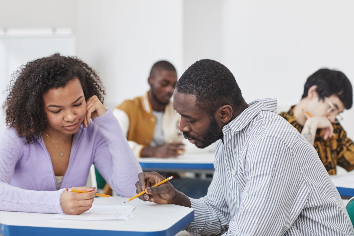 An advisor and student discussing written work at a classroom table.